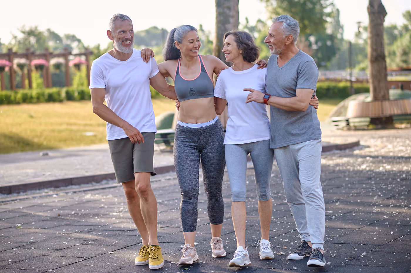 Healthy mature people standing together park hugging smiling healthy lifestyle enjoying outdoor activity — representing strength, vitality, and longevity.